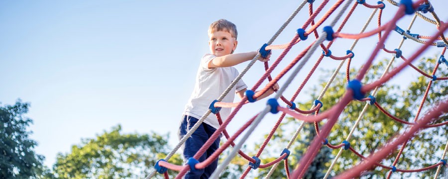 Junge auf Spielplatz Kletternetz