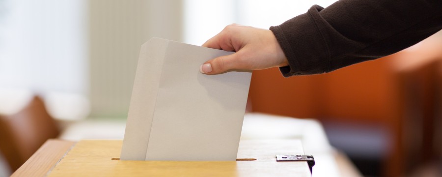Wähler legt Stimmzettel in Wahlurne