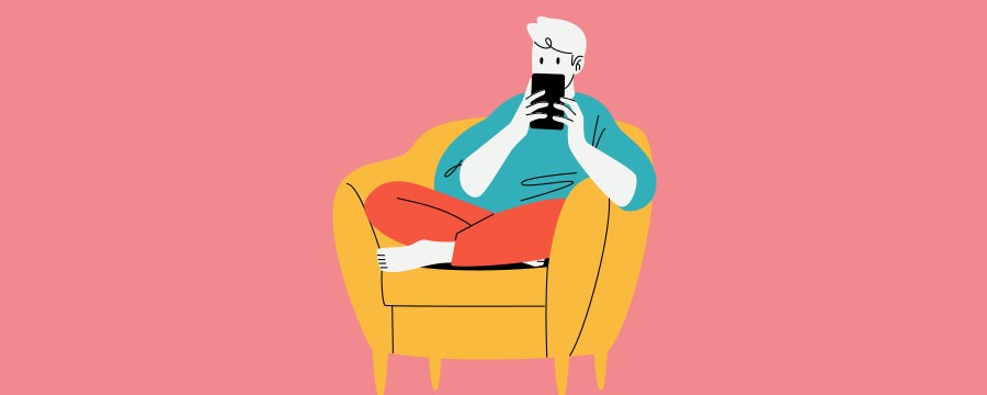 Mann sitzt im Sesssel und schaut auf sein Smartphone.