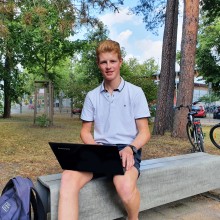 Schüler Sören Twietmeyer mit Laptop auf Bank vor der Schule
