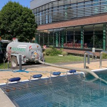 Ein Wässerwagen pumpt Wasser aus dem Außenbecken des Südstadtbads