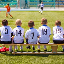 Kinder auf Bank am Sportplatz
