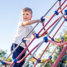 Junge auf Spielplatz Kletternetz